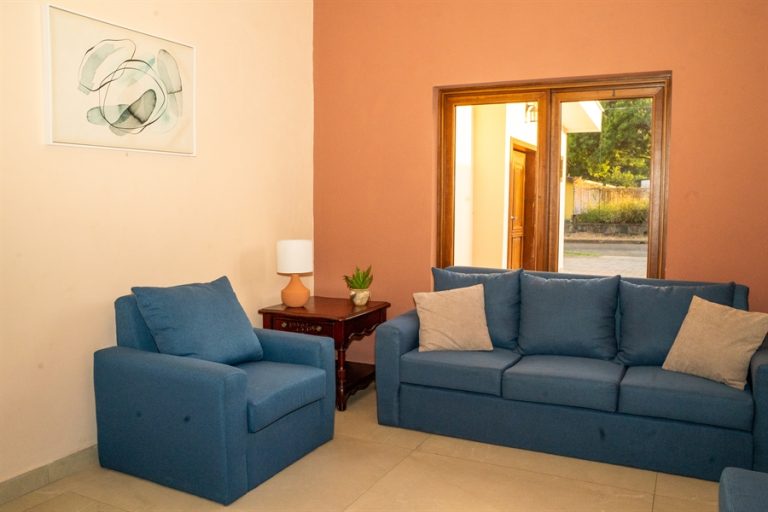 Sala de espera con sofás azules y mesa de centro para familiares en Funeraria El Alba