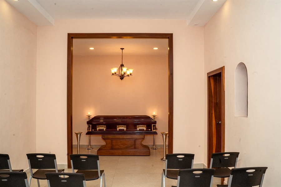 Sala de velación con ataúd, sillas para familiares e iluminación cálida en El Alba.