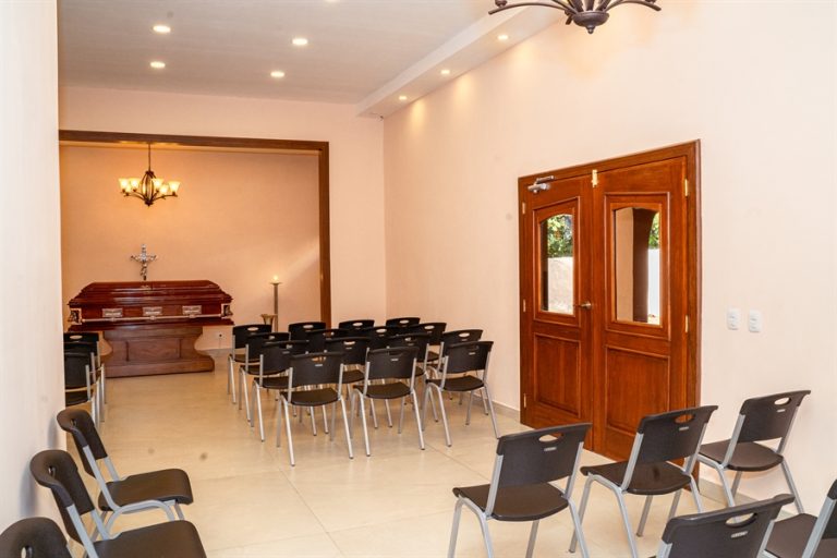 Capilla funeraria con ataúd, sillas para familiares y ambiente cálido de recogimiento