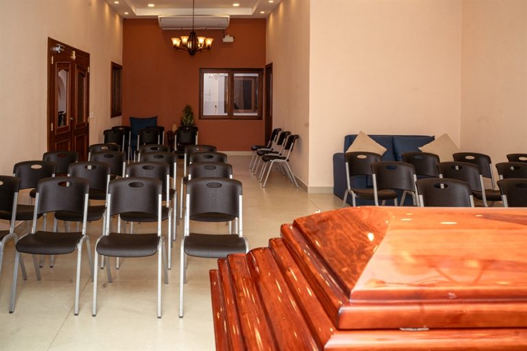 Sala de velación con ataúdes de madera natural y sillas para acompañantes