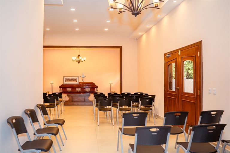 Capilla de velación con ataúd al frente, sillas ordenadas y ambiente sereno