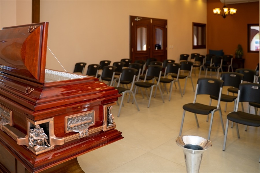 Capilla amplia con ataúd, sillas para acompañantes e iluminación cálida en Funeraria El Alba.