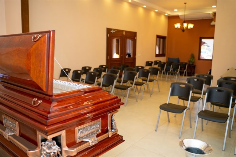 Sala de velación con ataúd abierto, sillas para familiares y ambiente de recogimiento