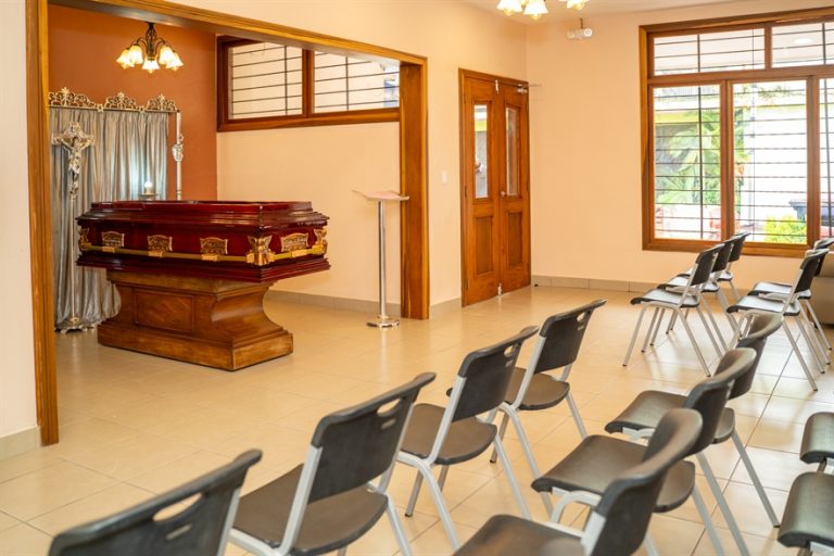 Sala de velación amplia con ataúd, sillas en hileras y ambiente sobrio en Funeraria El Alba