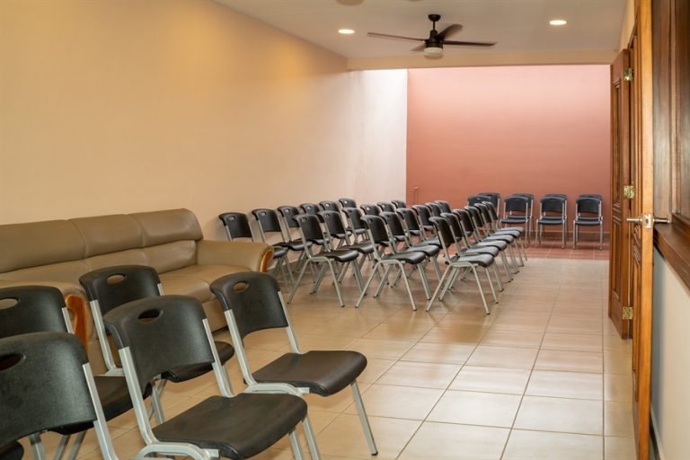 Sala de velación con paredes color coral y sillas ordenadas para acompañantes