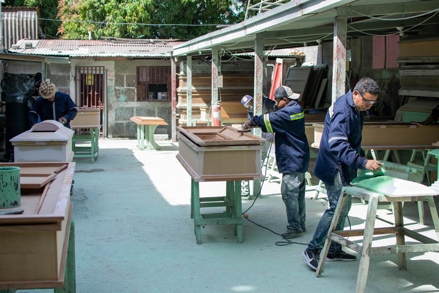 Carpinteros ensamblando ataúdes de madera en el taller de fabricación en Managua.