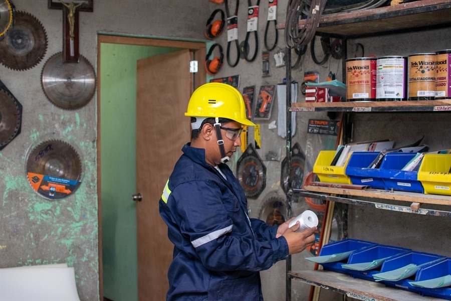 Operario con equipo de protección trabajando en el taller de fabricación de ataúdes.